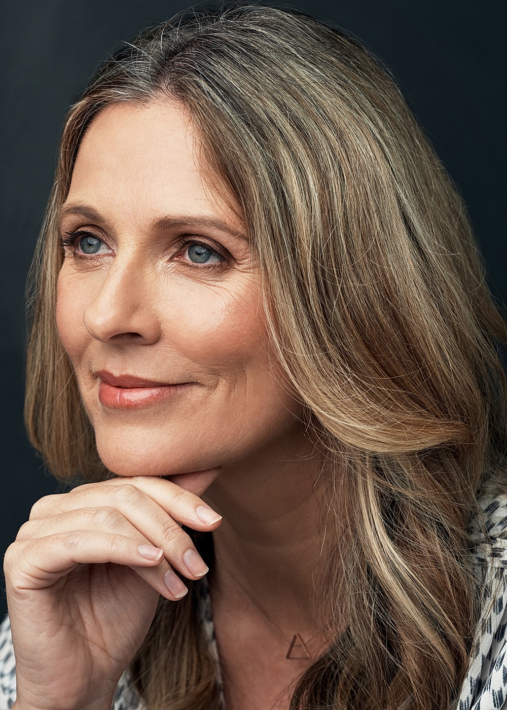 Thoughtful woman with long, wavy hair.